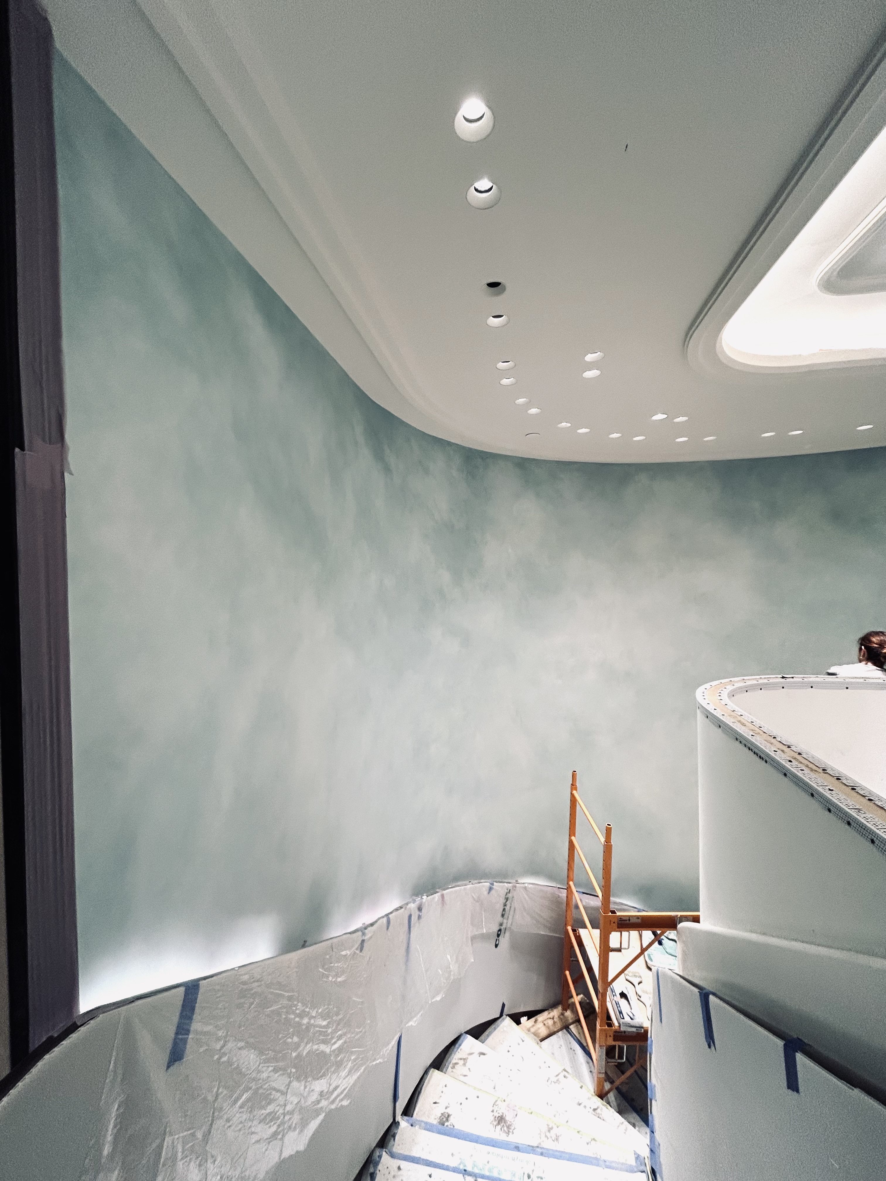 Blue-green cloud-washed walls around a curved stairwell