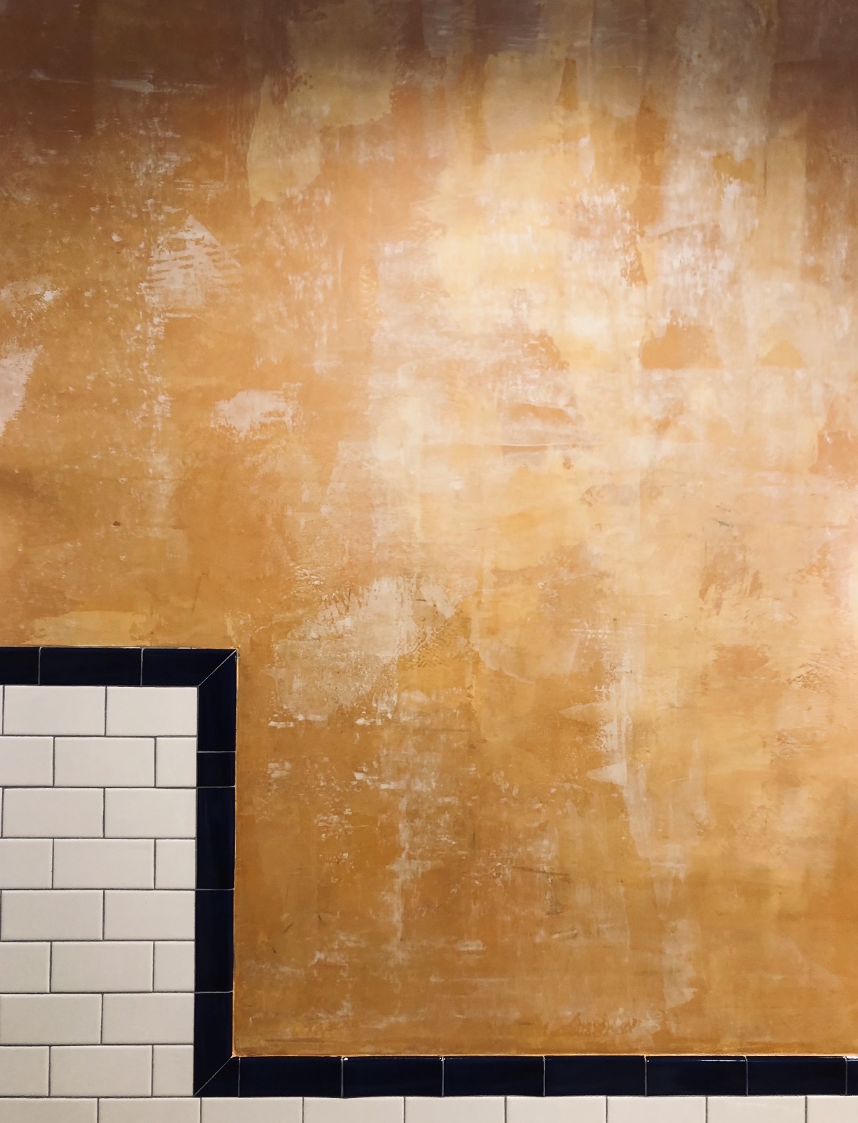 Aged ochre plaster finish above black and white tile